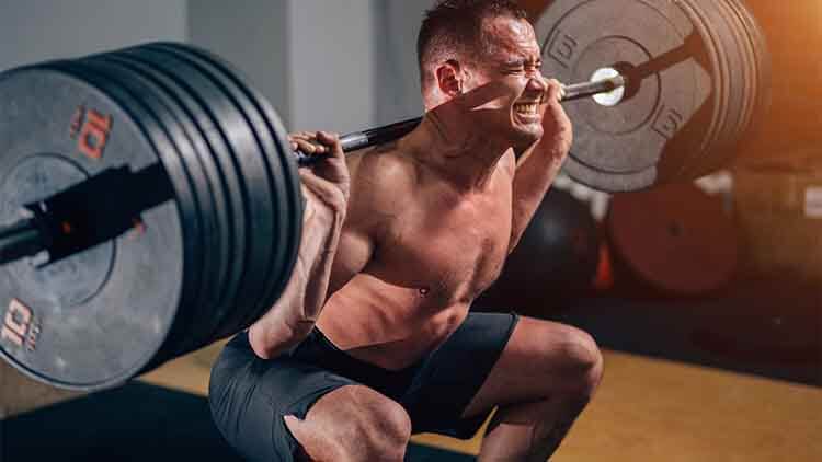 Homme musclé formation squats avec haltères sur les épaules.