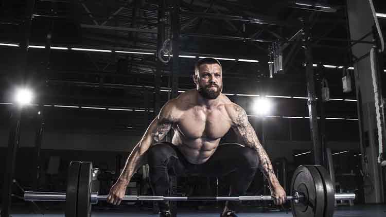 Homme torse nu musclé se préparant à soulever un haltère